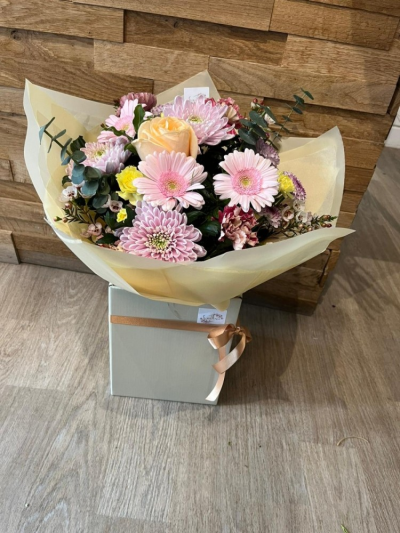 As fresh as a daisy - This elegant handtie is filled with seasonal cut flowers in shades of peach, pink and yellow. Wrapped in tissue paper and celophane then presented in a box that comes with water. The perfect gift to make your loved one smile even on their darkest days!!