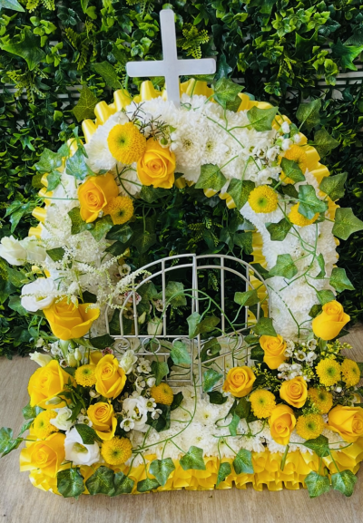 Gates of heaven - A beautifully symbolic and thoughtfully designed Gates of Heaven funeral tribute, created to represent peace, faith and eternal rest. This elegant arrangement features a circular arch of fresh white chrysanthemums, accented with vibrant yellow roses and yellow spray chrysanthemums, symbolising hope, remembrance and everlasting love.

Delicate ivy trails throughout the design, adding softness and a sense of serenity, while the tribute is finished with a white cross at the top and a decorative gate detail at the centre, representing the passage into eternal peace. Yellow ribbon edging completes the piece, bringing warmth and light to this meaningful tribute.

Ideal for religious services, memorials or celebrations of life, this tribute can be personalised with alternative colour schemes or floral choices to create a heartfelt and fitting farewell.

A truly touching and symbolic tribute, offering comfort and beauty during a time of remembrance.